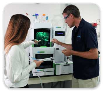 Two people in a lab pointing to a machine display